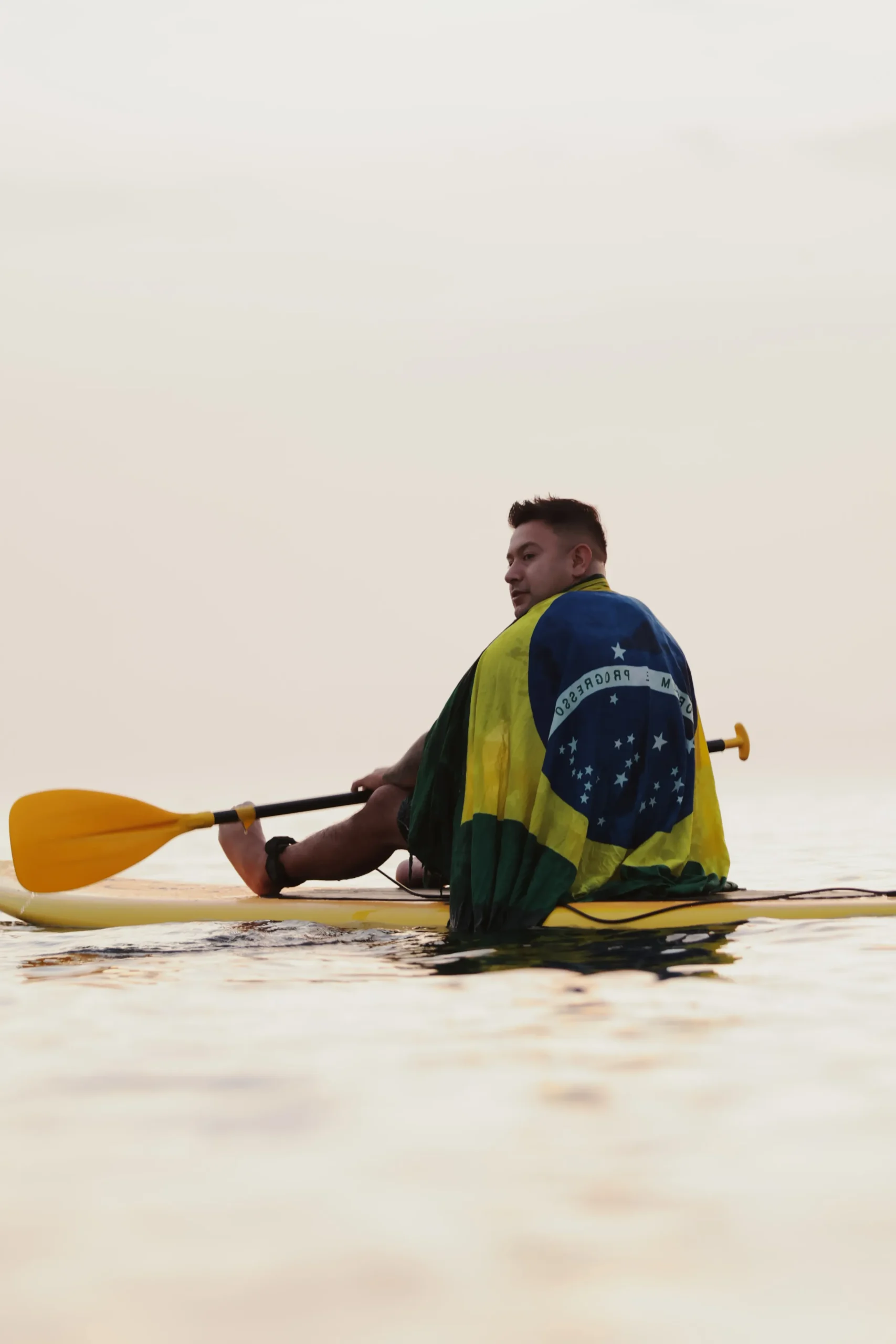Stand up paddle Copacabana com o Gladiadores SUP: conexão com o mar e orgulho representado pela bandeira do Brasil em um momento único.